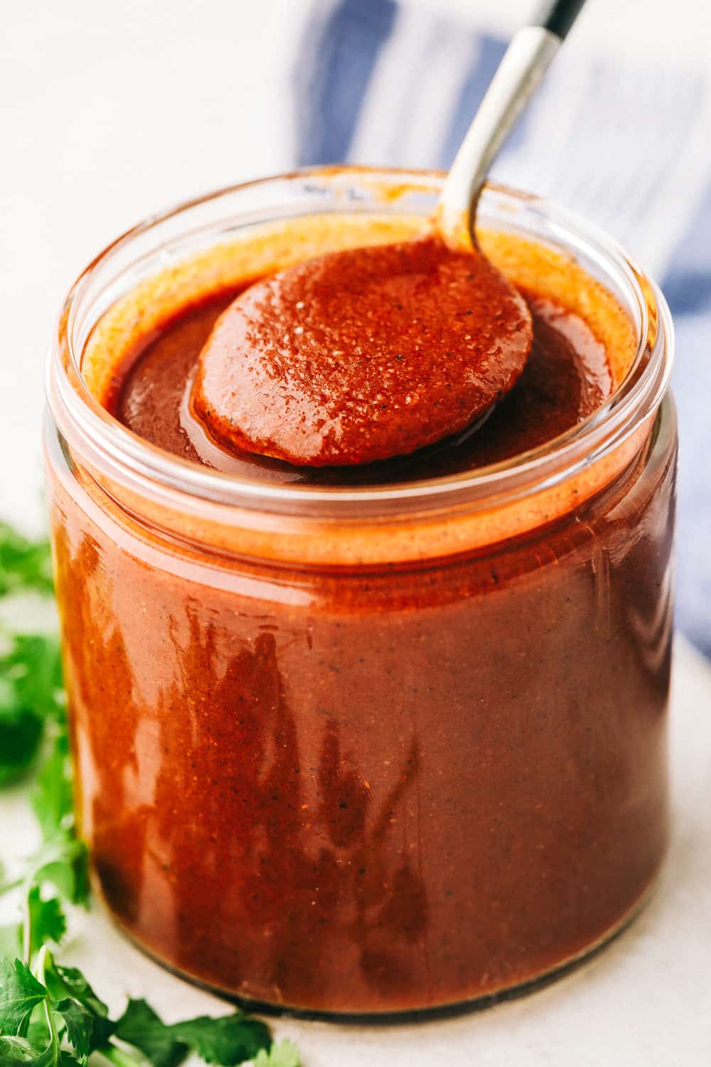 Homemade enchilada sauce in a jar being spooned out. 