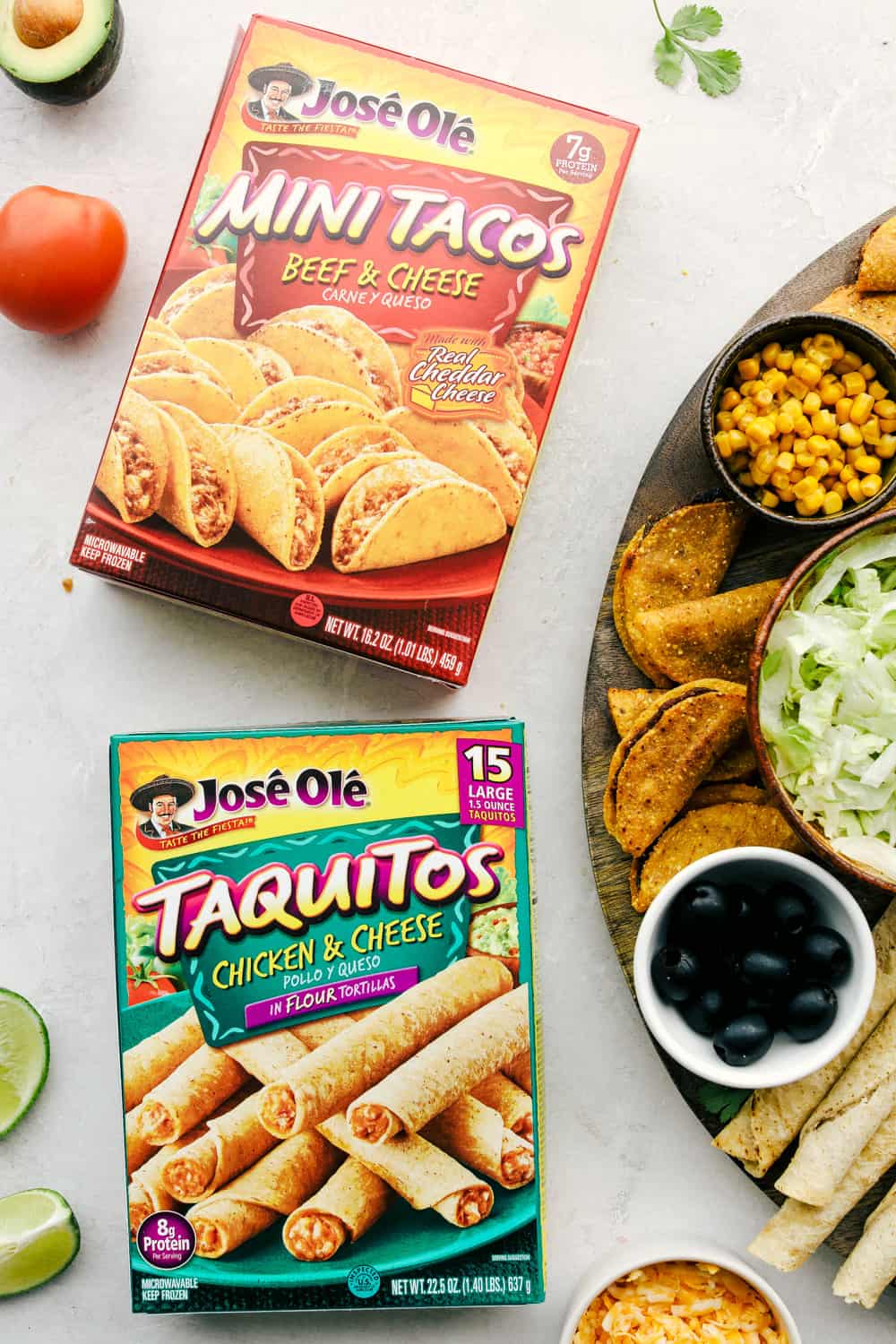 Mini tacos and taquitos in a box with the taco board on its side. 