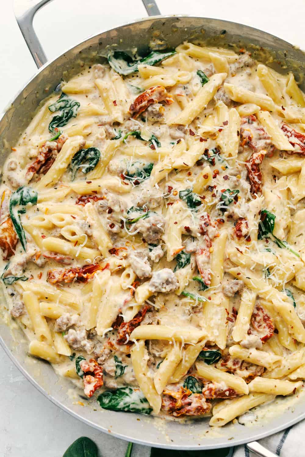 Creamy Tuscan Sausage Pasta in a pan garnished with parmesan. 