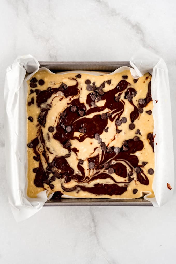 Swirled banana bread and brownie batter in a square pan.