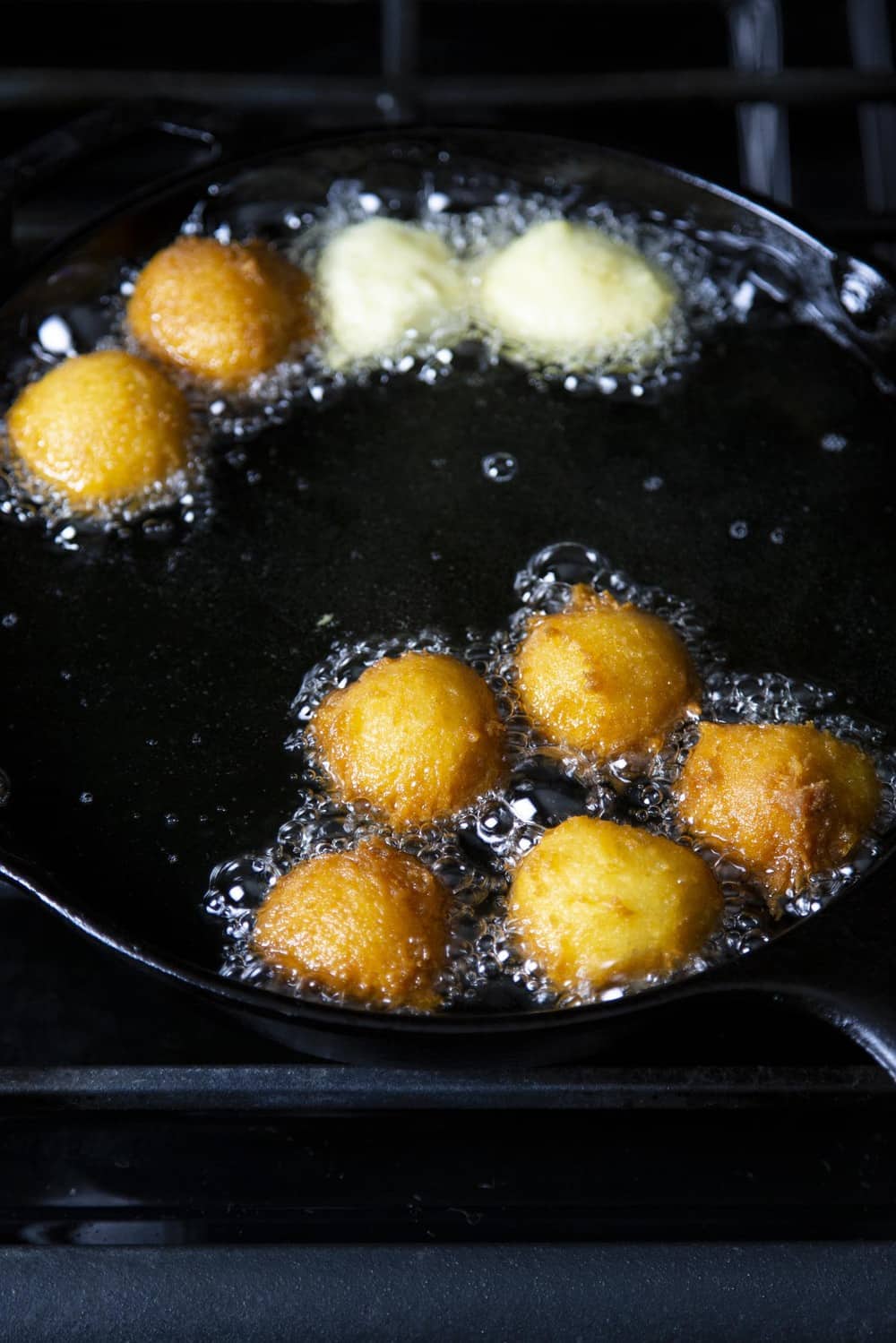 Donut holes frying in a pan of oil.