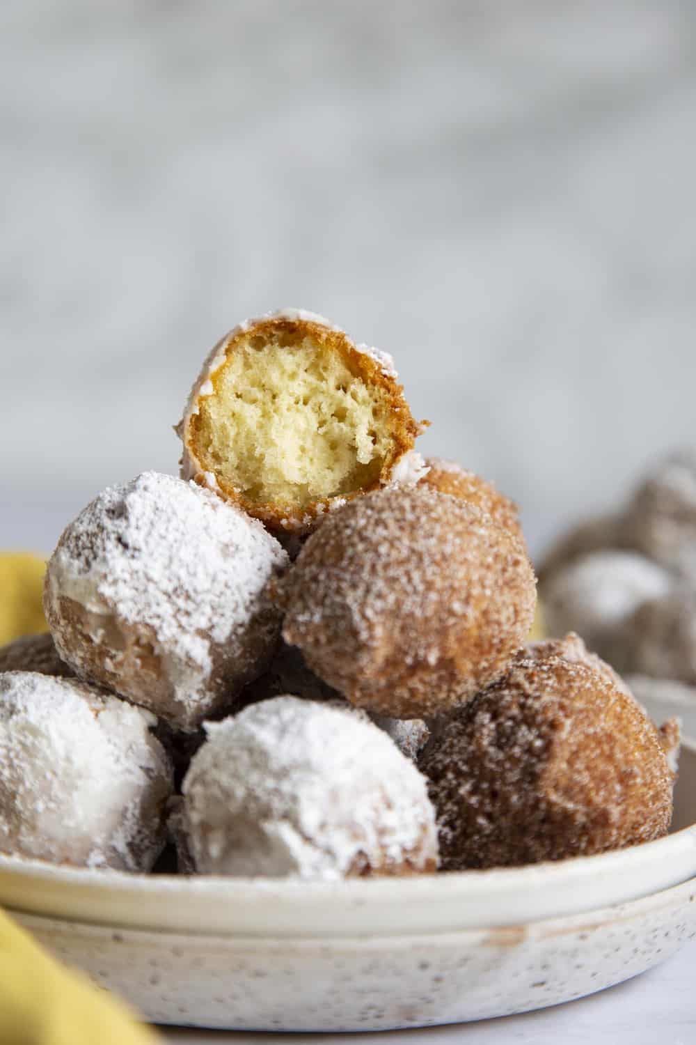 A tower of donut holes with one half eaten on top. 
