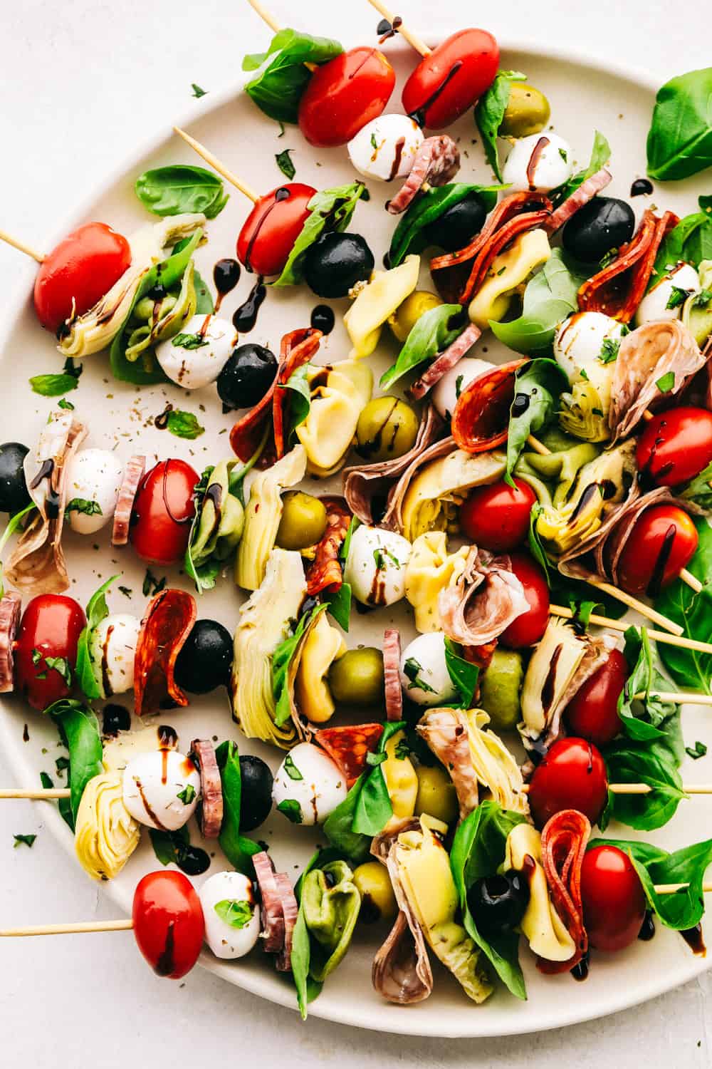 Antipasto skewers with cheese, olives, meats, spinach and cheese on a plate.