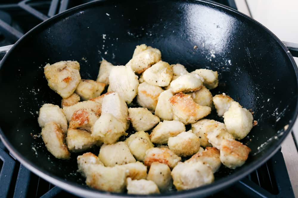 My easy Cashew Chicken recipe skips the breading and frying, but you still get that crispy tender chicken! It all comes together in my flavorful sauce! Pieces browning in a wok.