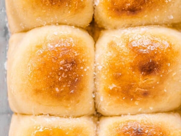 Potato buns in a baking pan with honey butter on top.