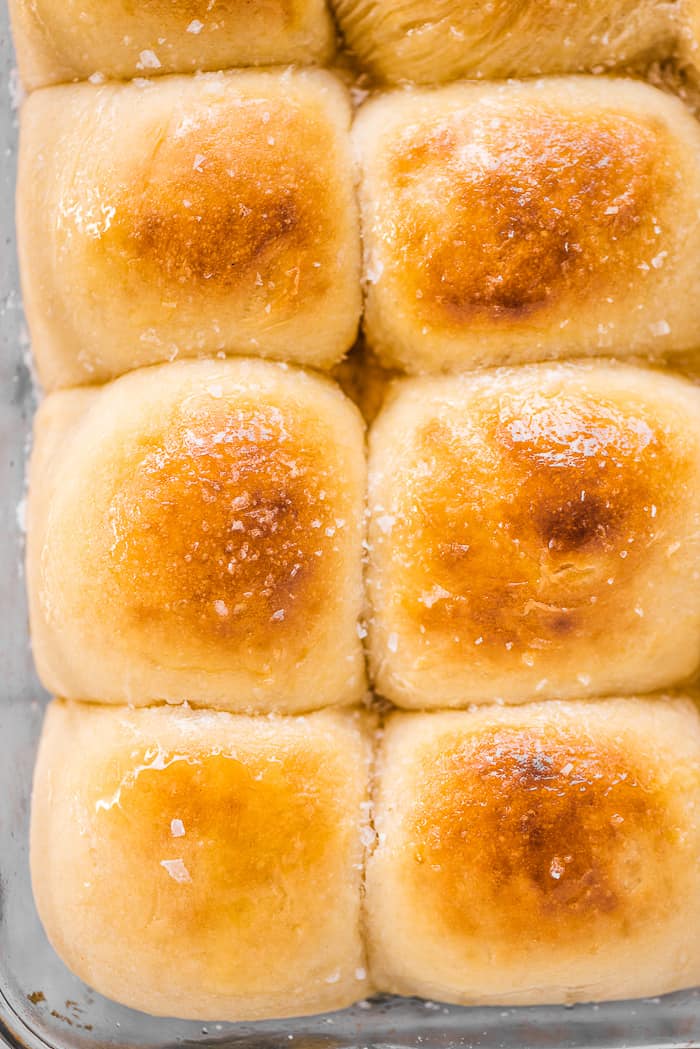 Potato buns in a baking pan with honey butter on top.