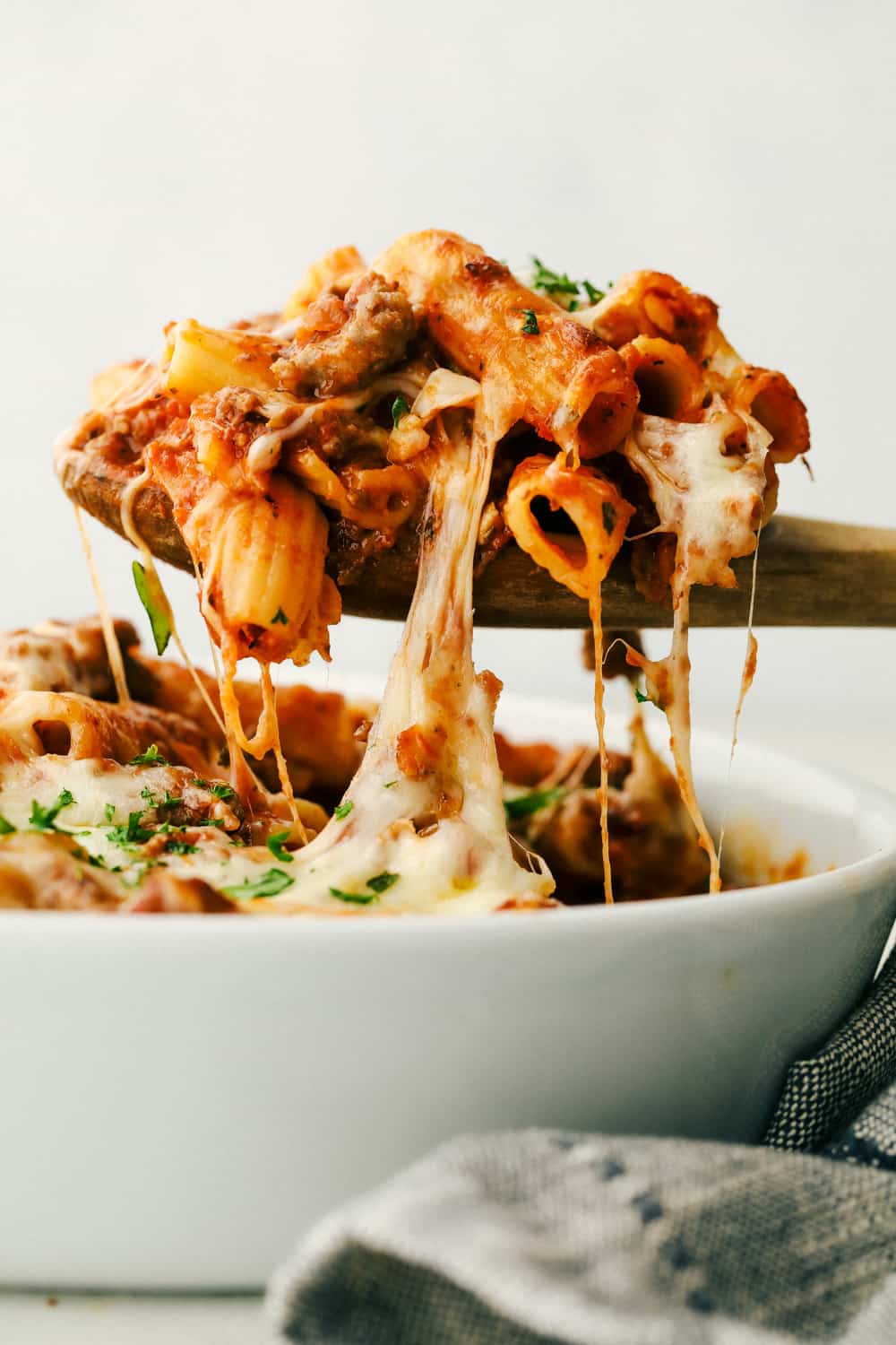 Baked rigatoni being spooned out of a bowl.