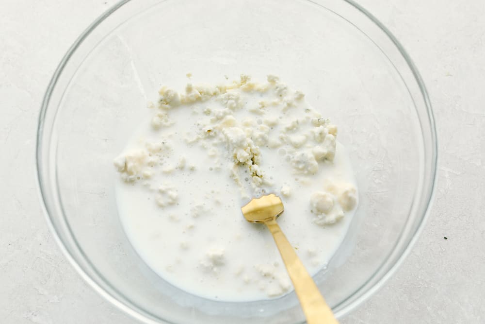 Mashing the blue cheese with the buttermilk in a bowl. 