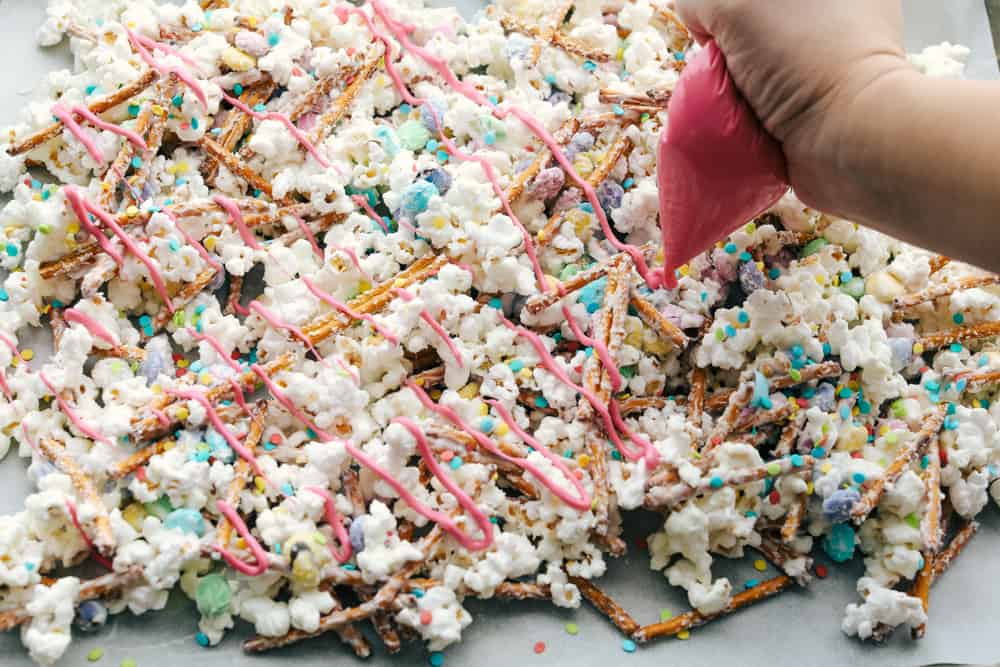 Adding colorful candy melt drizzles to the cooking popcorn mixture. 