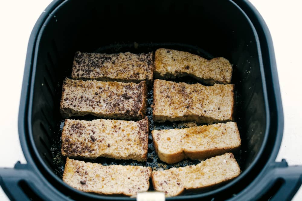 Placing french toast sticks in air fryer basket. 