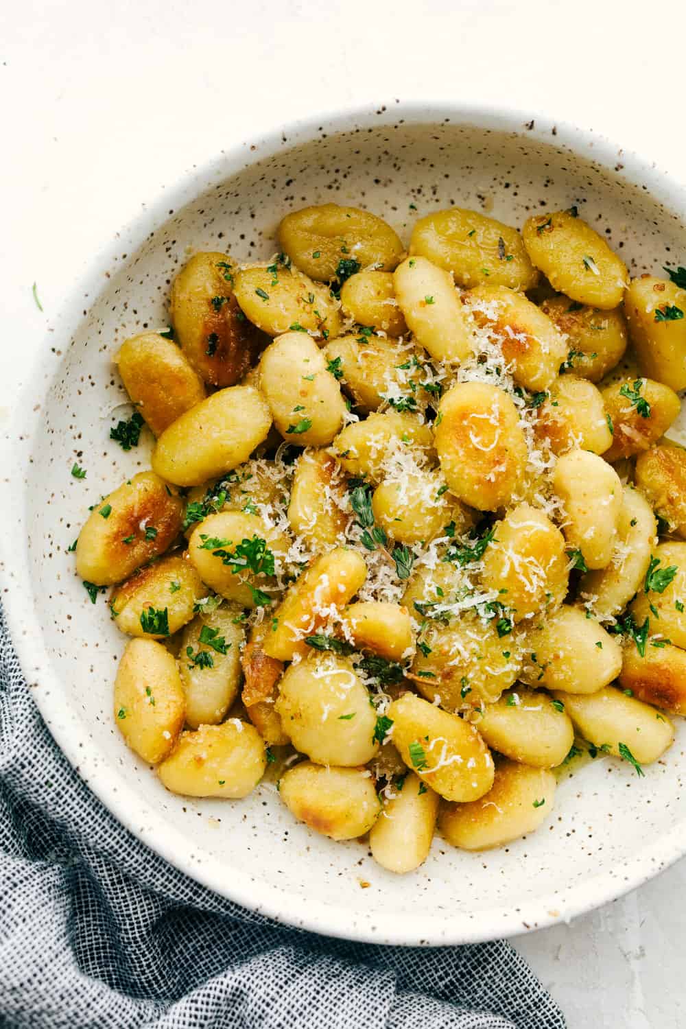 Fried gnocchi with browned butter in a bowl and parmesan cheese. 