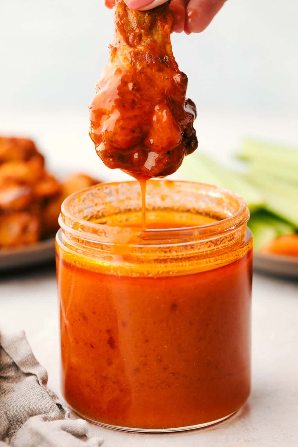 Dipping a chicken leg in homemade buffalo sauce. 