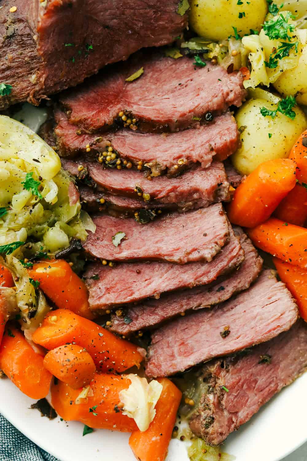 Sliced corned beef, cabbage, carrots, and potatoes on a plate. 