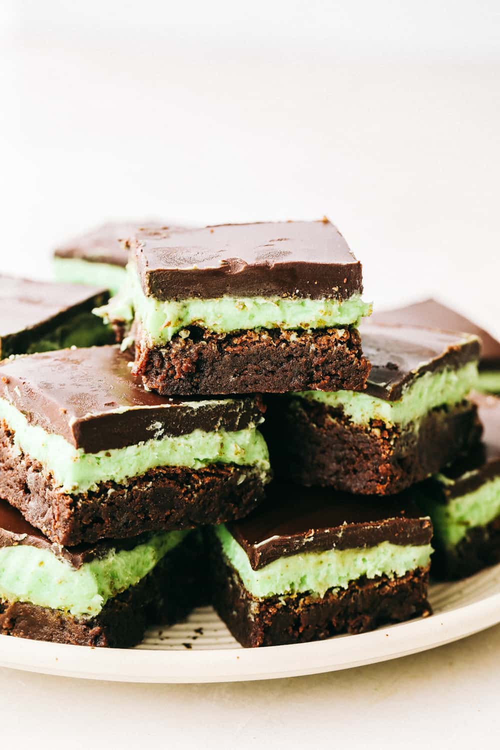 Layered mint brownies stacked on a white plate. 