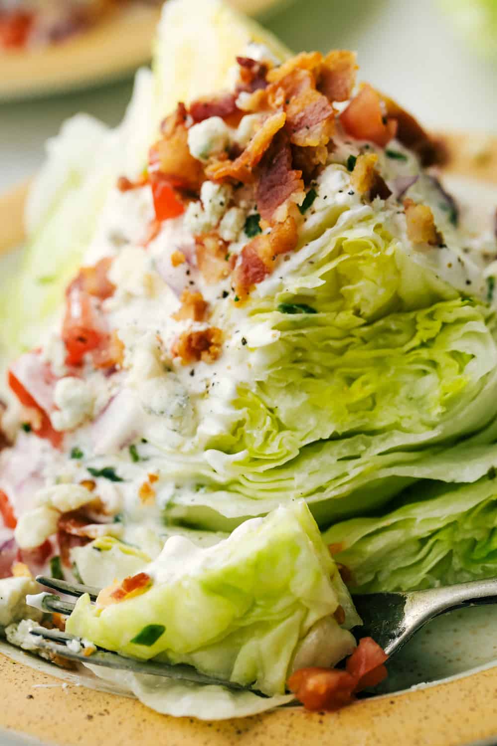 Up close picture of a wedge salad on a plate with a fork.