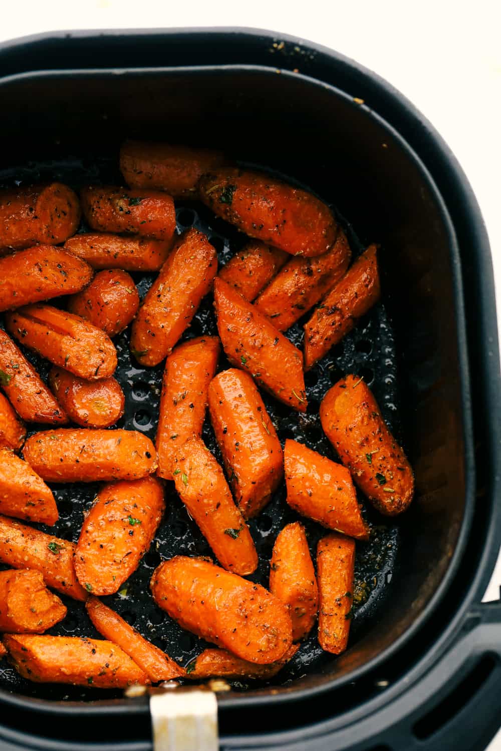 Air fryer carrots seasoned in air fryer basket.