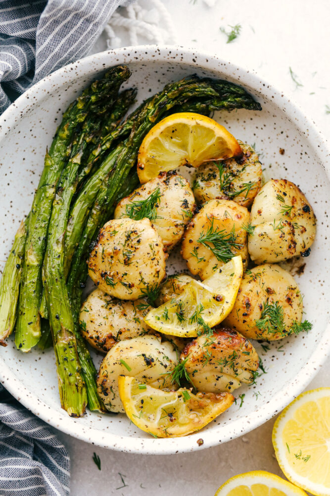 Scallops with asparagus and lemons in a bowl. 