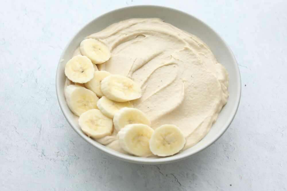 Smoothie in a bowl topped with bananas. 
