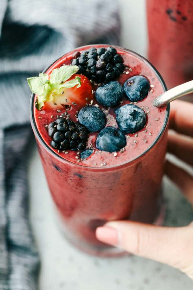 Holding a glass of berry smoothie getting ready to drink. 