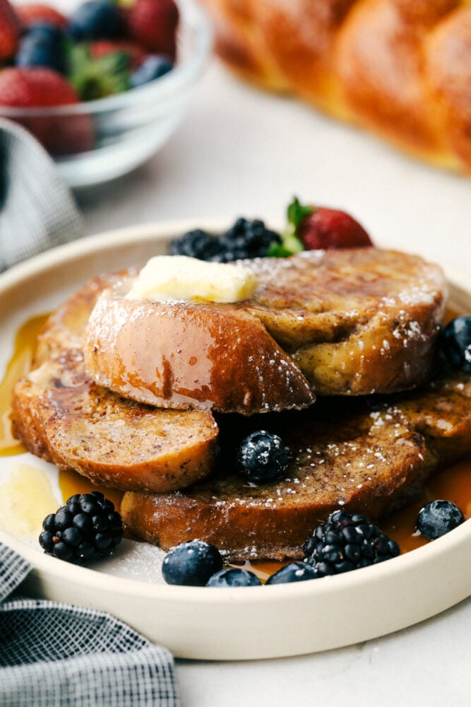 Challah French Toast on a plate with butter and berries. 