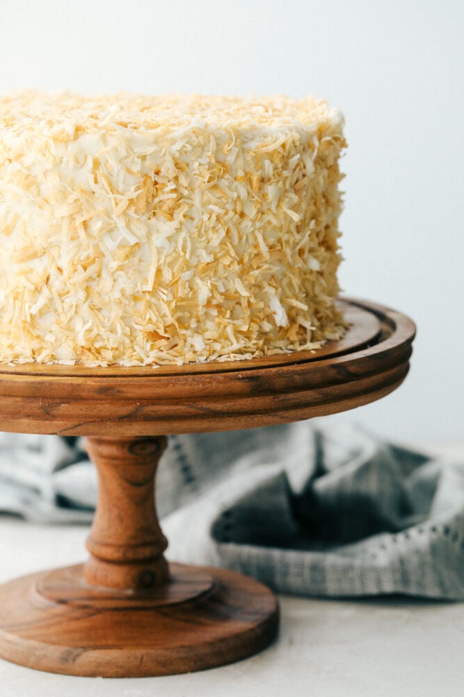 Coconut cake on a pedestal ready to cut.  