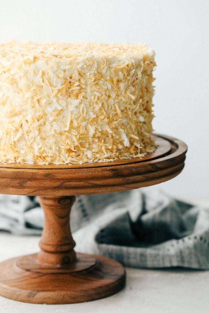 Coconut cake on a pedestal ready to cut. 