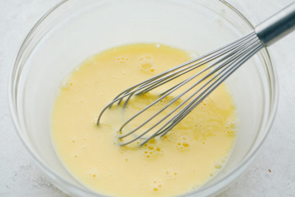 Mixing eggs for cooking in a glass bowl.