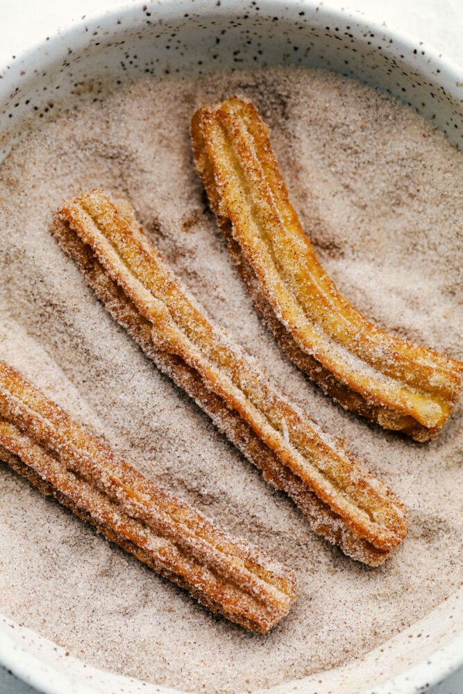 Rolling the Churros in cinnamon and sugar. 