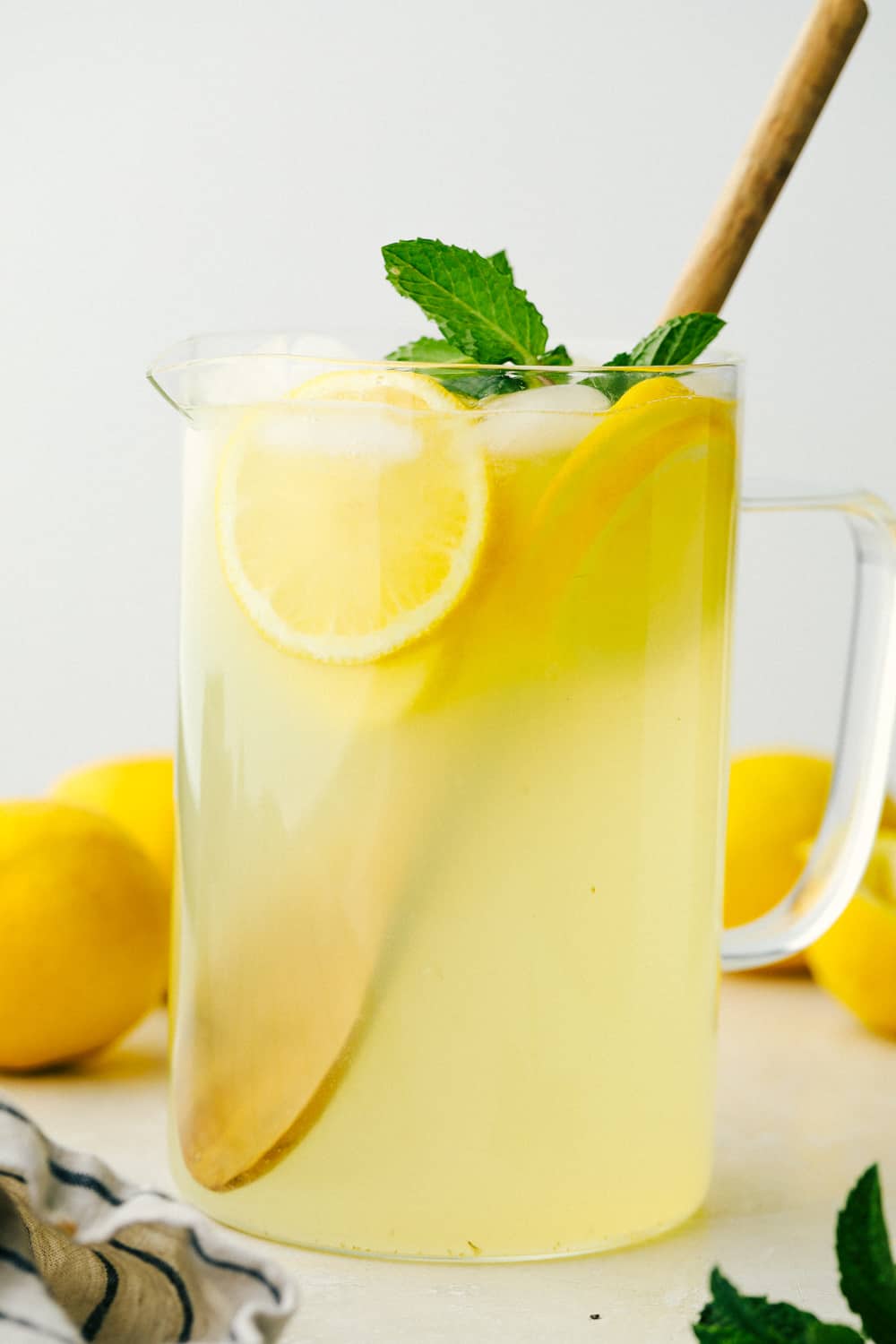 A pitcher of homemade lemonade with lemons. 