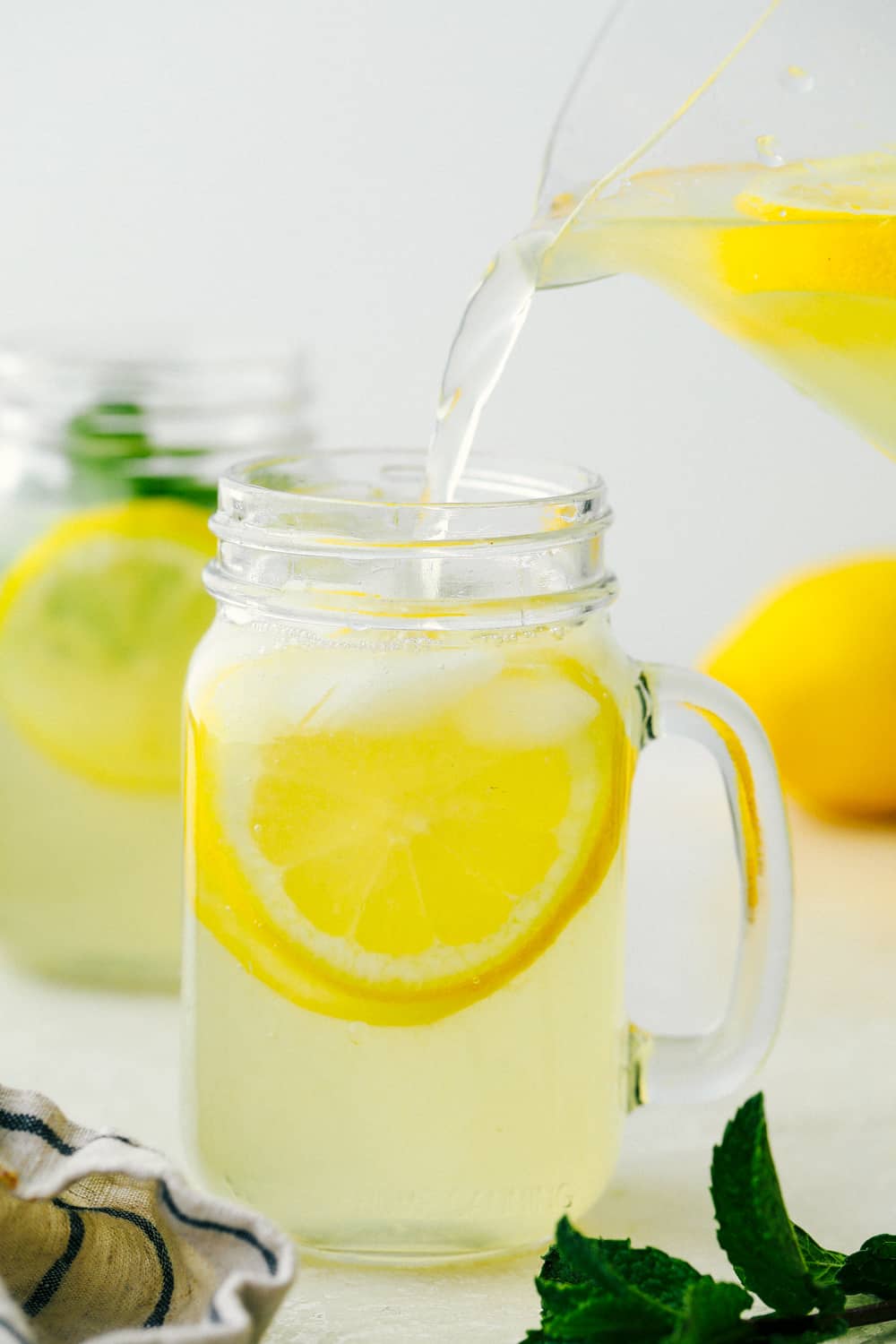 Pouring lemonade in glass mason serving jars. 