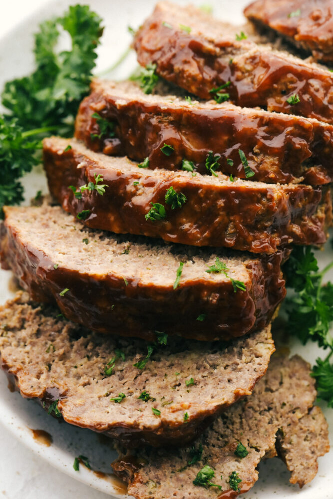 The whole meatloaf sliced up on a plate with parsley garnish. 