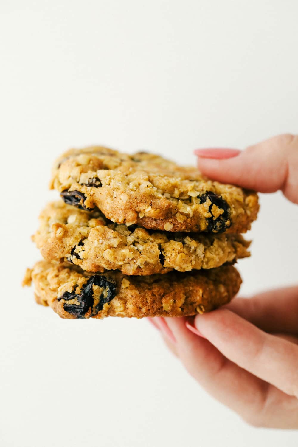 Holding a stack of three cookies. 