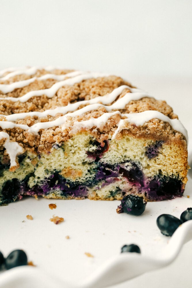 A cross cut of the baked blueberry crumb cake with frosting drizzle. 