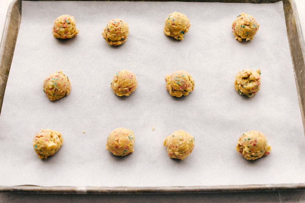 Formed cookie dough balls on a parchment lined cookie sheet. 