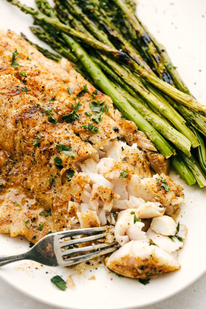 Taking a bite of the cod with a fork. 