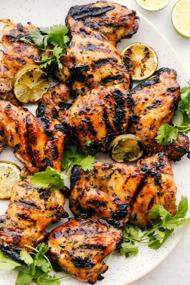Perfectly grilled tender and juicy chicken marinated in a honey lime cilantro marinade. The flavor of this chicken is incredible! The grilled honey lime cilantro chicken on a white platter.
