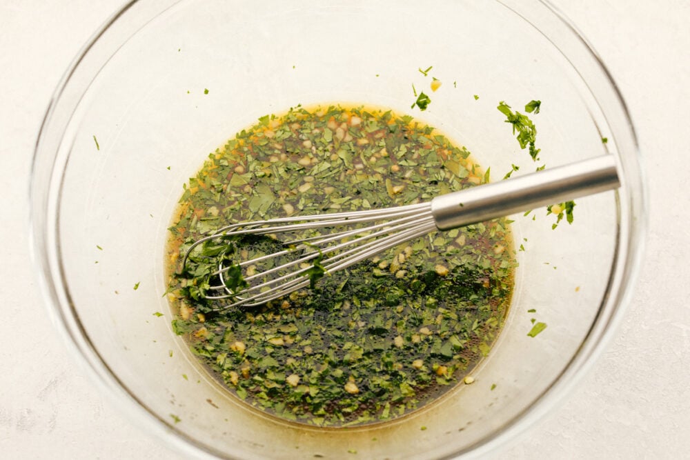 A bowl with marinade all mixed together with a whisk. 