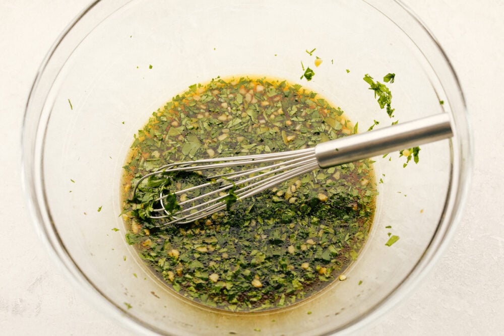 This Honey Lime Chicken is perfectly grilled tender and juicy meat. Marinated in a honey lime cilantro marinade, the flavor of this chicken is incredible! A bowl with marinade all mixed together with a whisk.