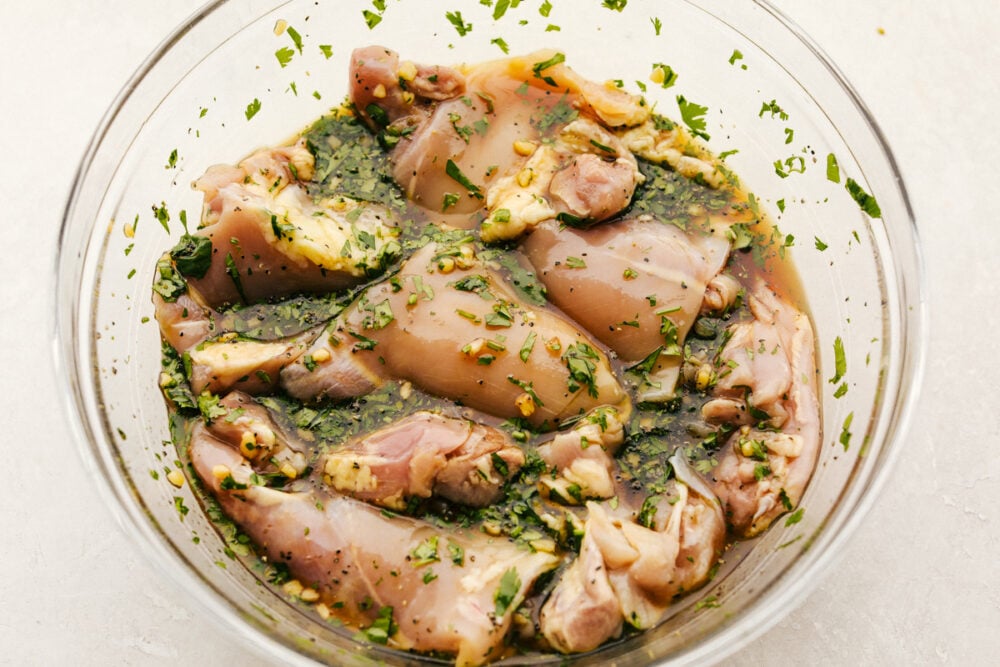 Grilled Honey Lime Cilantro Chicken is perfectly grilled tender and juicy chicken. Marinated in a honey lime cilantro marinade, the flavor of this chicken is incredible! chicken marinating in the bowl of seasonings.