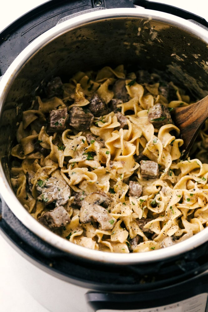 Instant Pot Stroganoff being stirred with a wooden spoon. 