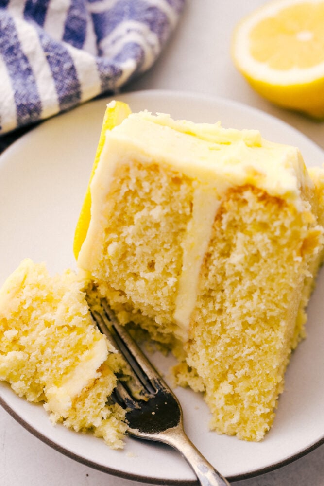 Using a fork to take a bite of the cake with lemon frosting. 