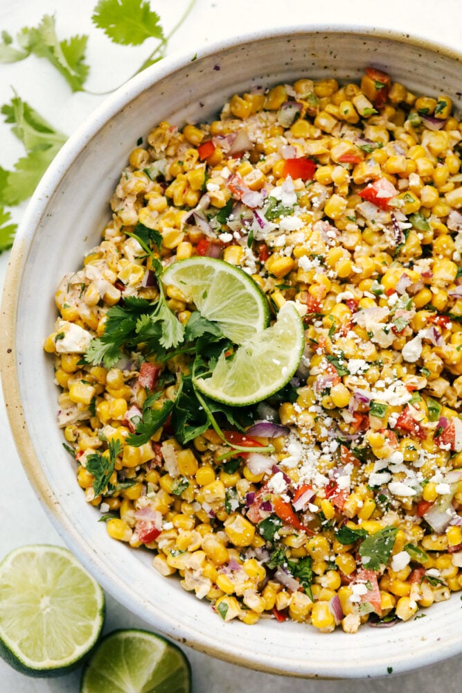 Mexican Corn Salad garnished with limes and cilantro. 