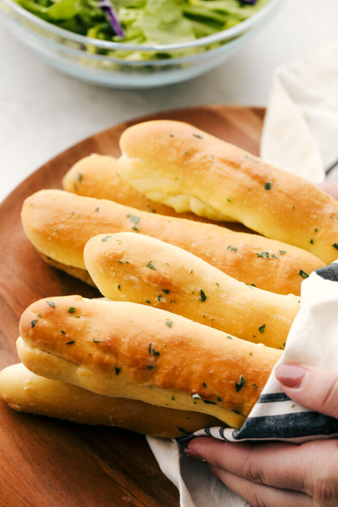 Placing breadsticks on a board wrapped in a towel and ready to eat. 