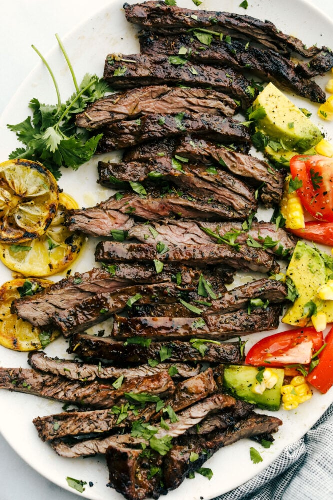 Sliced grilled skirt steak on a plate with garnishes. 