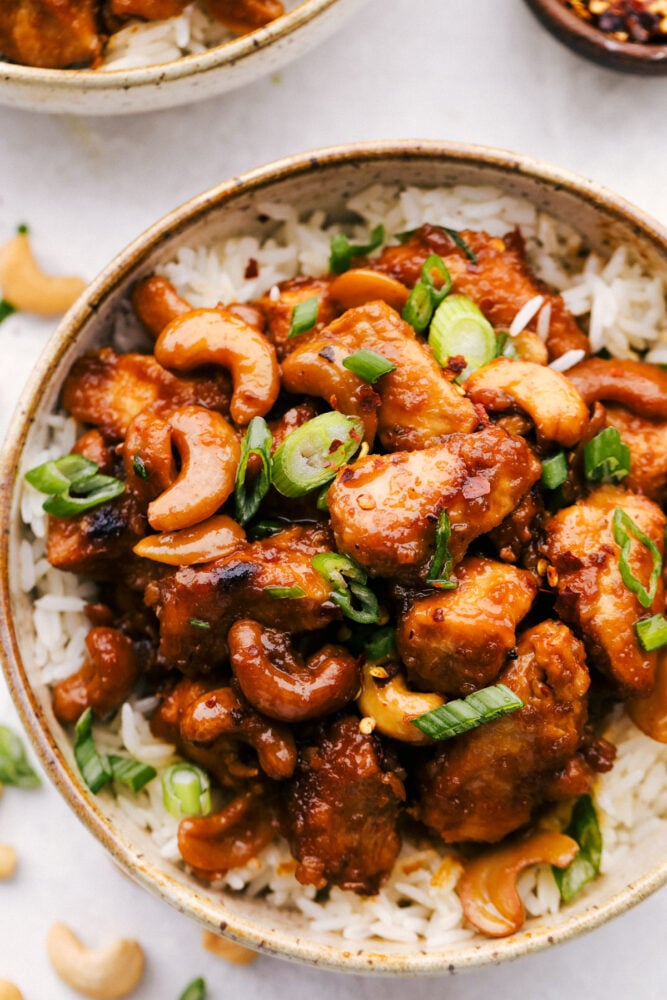 Sitting on a bed of rice, slow cooker cashew chicken in a bowl. 