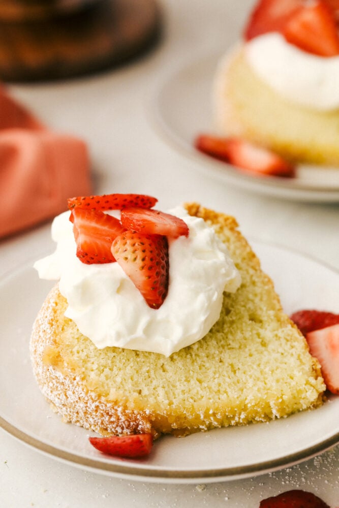 A piece of sour cream pound cake with whipped cream and strawberries. 