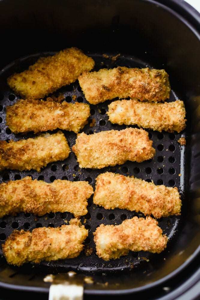 Cooked fish sticks in the basket of the air fryer. 