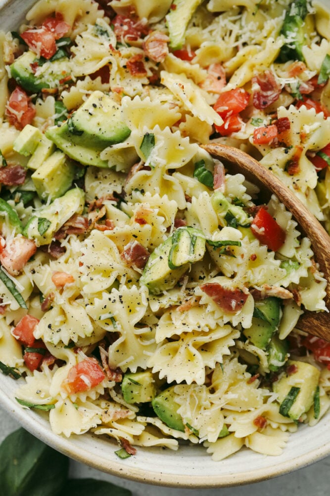 Up close pasta salad with a wooden spoon.