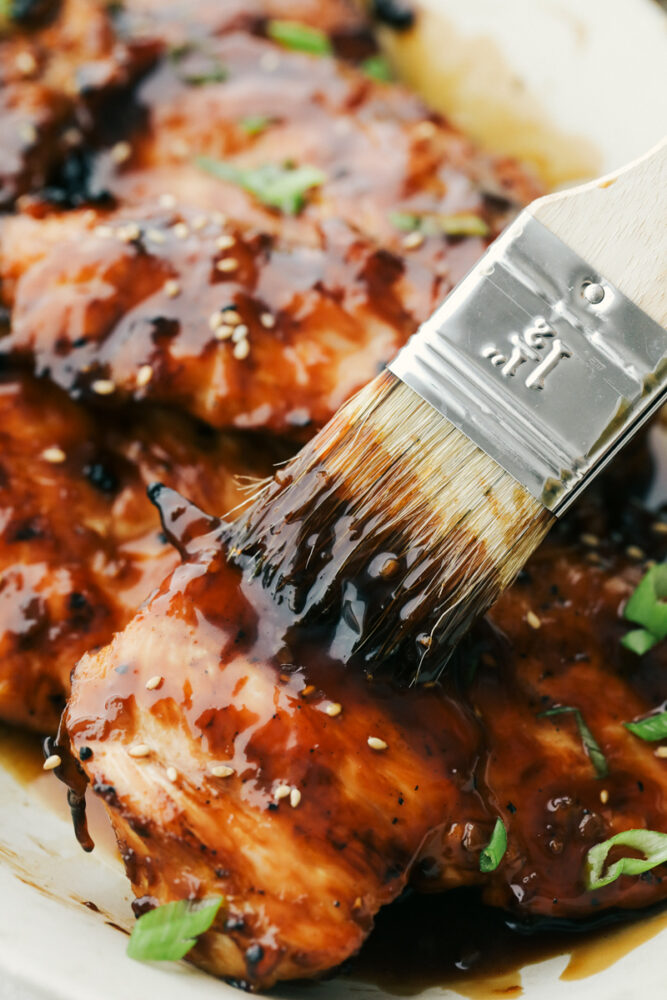 Basting the rest of the teriyaki sauce onto cooked chicken. 