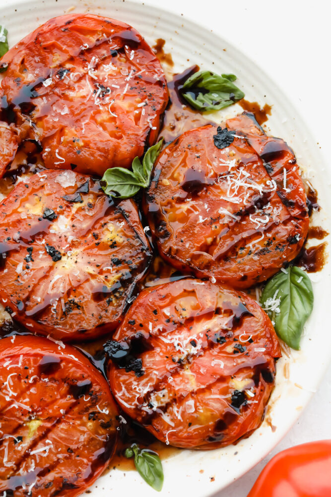 Grilled tomatoes on plate with balsamic vinegar glaze.